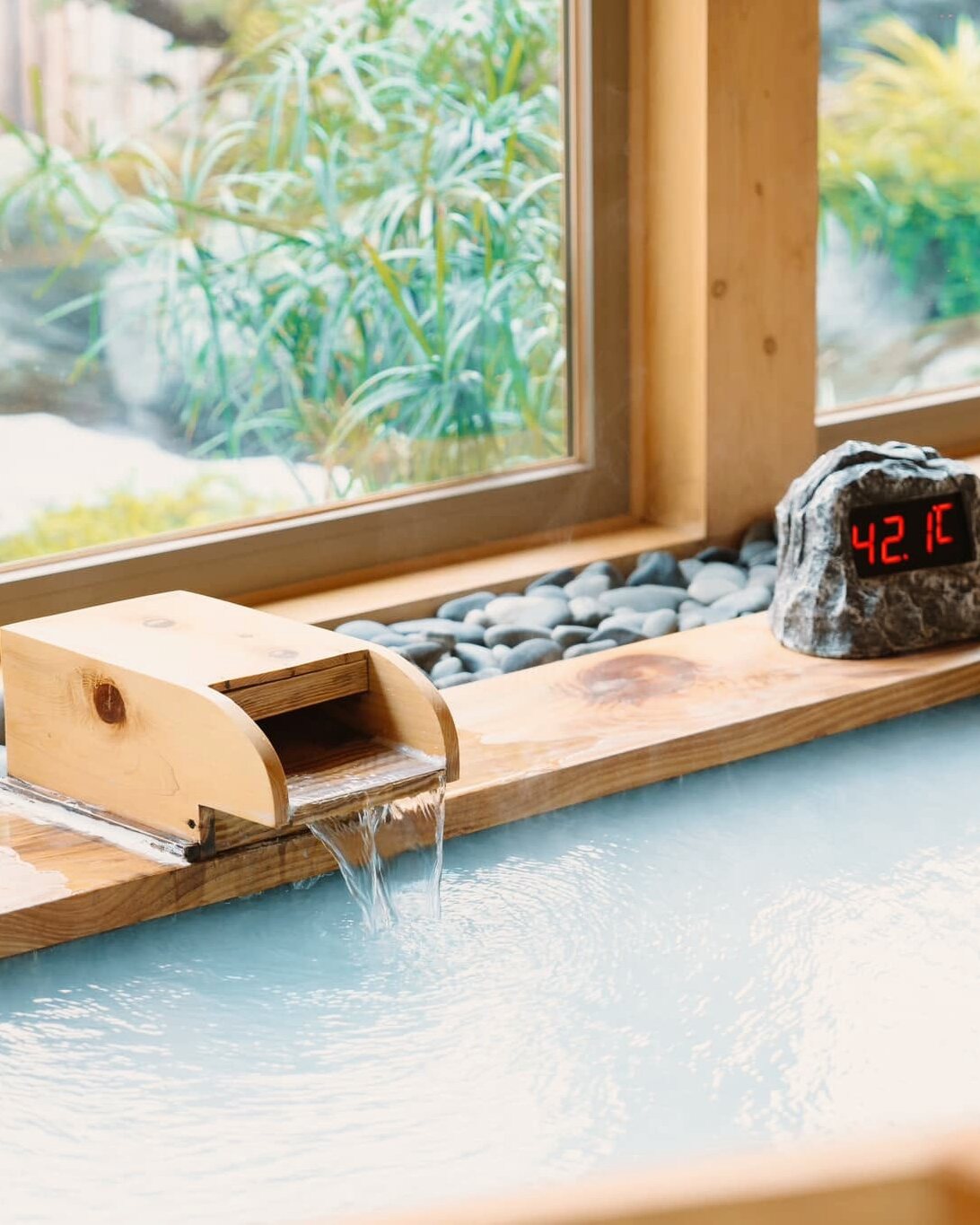 Vòi nước khoáng đổ vào mặt bể onsen tĩnh lặng